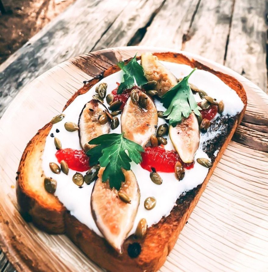 Palm leaf plates France — areca palm leaf serving plate with rustic toast topped with figs, pomegranate, fresh parsley and pumpkin seeds, artisanal Mediterranean presentation for French distributors, HoReCa procurement and organic-channel buyers