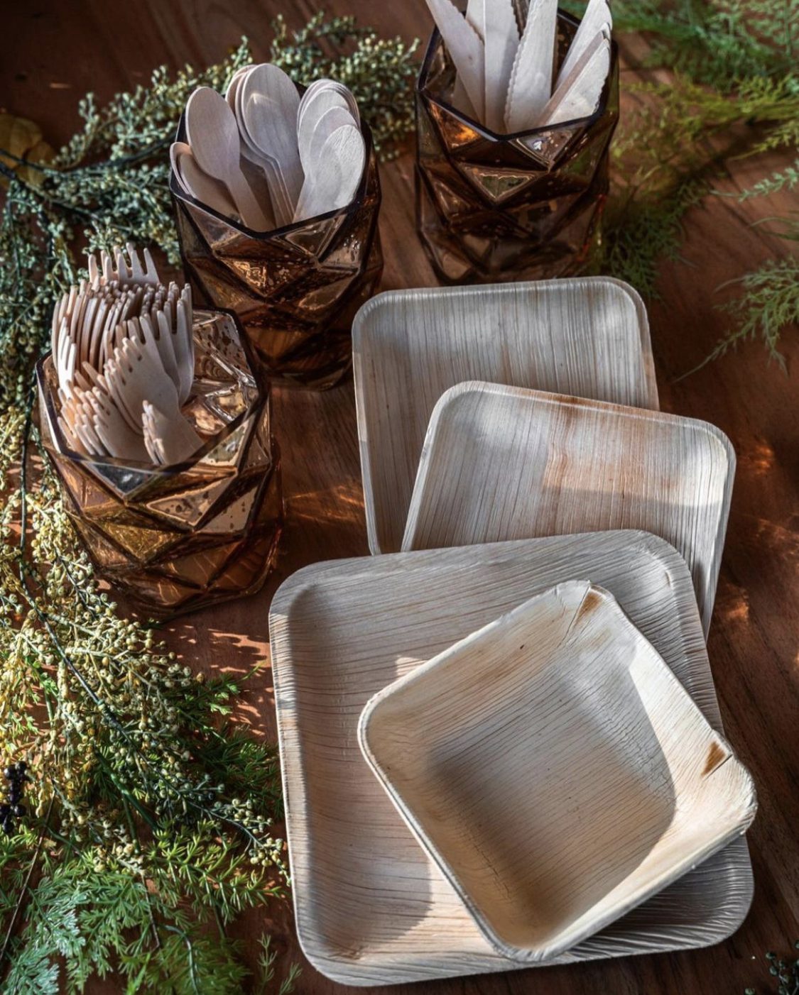 Areca palm leaf plates and bowls in lifestyle picnic service — salad, fresh fruit platter, and wrap rolls plated for outdoor dining, illustrating Ecodyne wholesale tableware in real HoReCa use for Norwegian distributors and event caterers